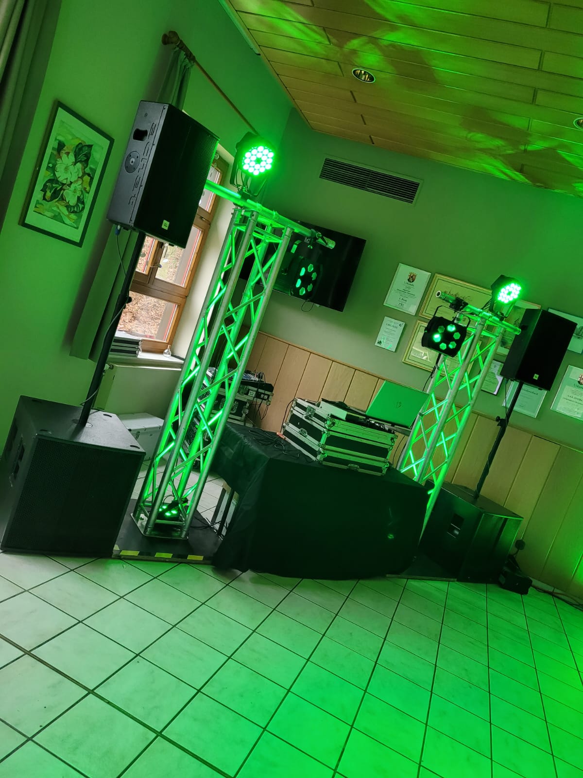DJ-Setup mit Traversen-System, Lautsprechern, Subwoofern und grüner Beleuchtung in einem Saal